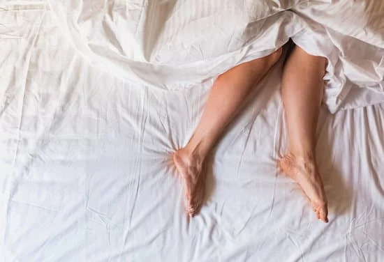Jambes allongées dans un lit