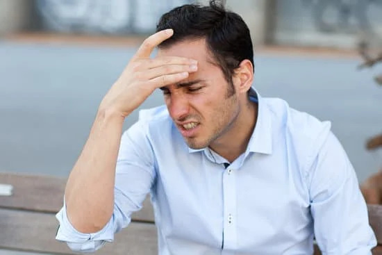 Un homme se tient la tête, il pourrait souffrir d'un trouble neurologique.