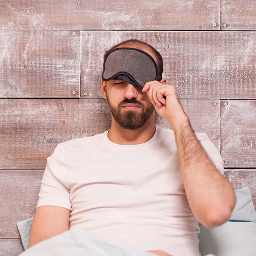 Un homme met un masque de sommeil sur ses yeux