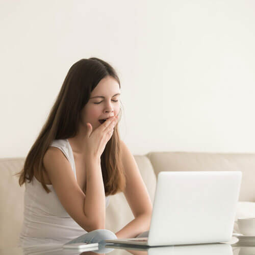 Une femme baille devant son écran d'ordinateur portable